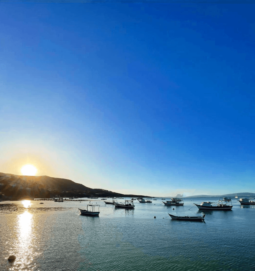 Barcos ancorados em águas calmas ao amanhecer na Praia do Tinguá
